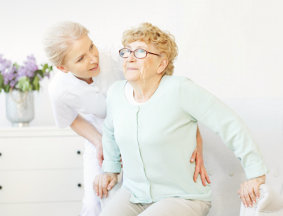 Caregiver assisting the elder woman to stand