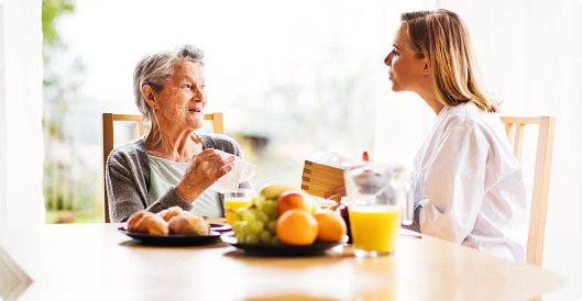 Caregiver and an elder woman having a conversation while eating